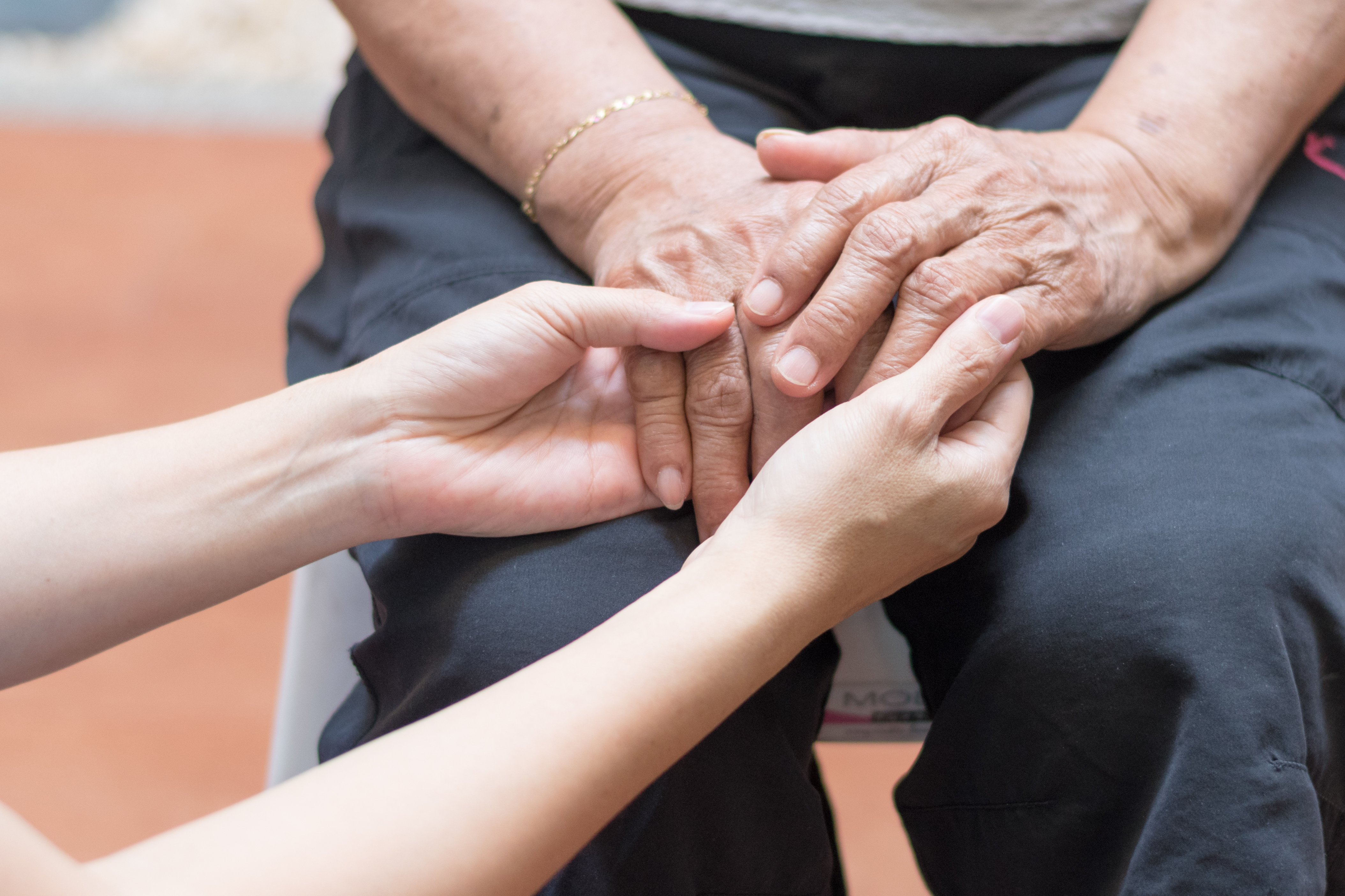 Elderly female hand holding hand of young caregiver at nursing home.Geriatric doctor or geriatrician concept. Doctor physician hand on happy elderly senior patient to comfort in hospital examination