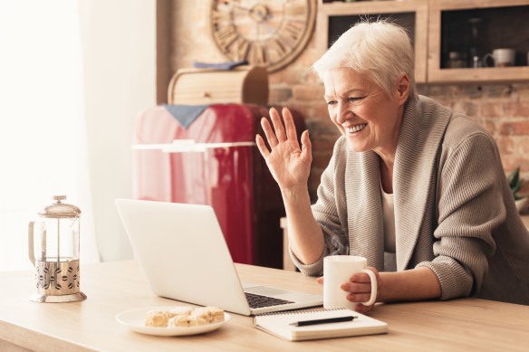 Elderly woman making video call on laptop in kitchen